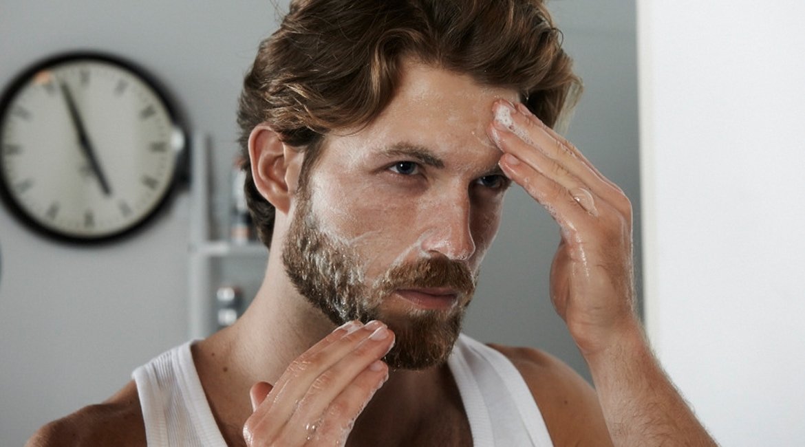 Ein Mann verteilt ein Reinigungsprodukt in seinem Gesicht
